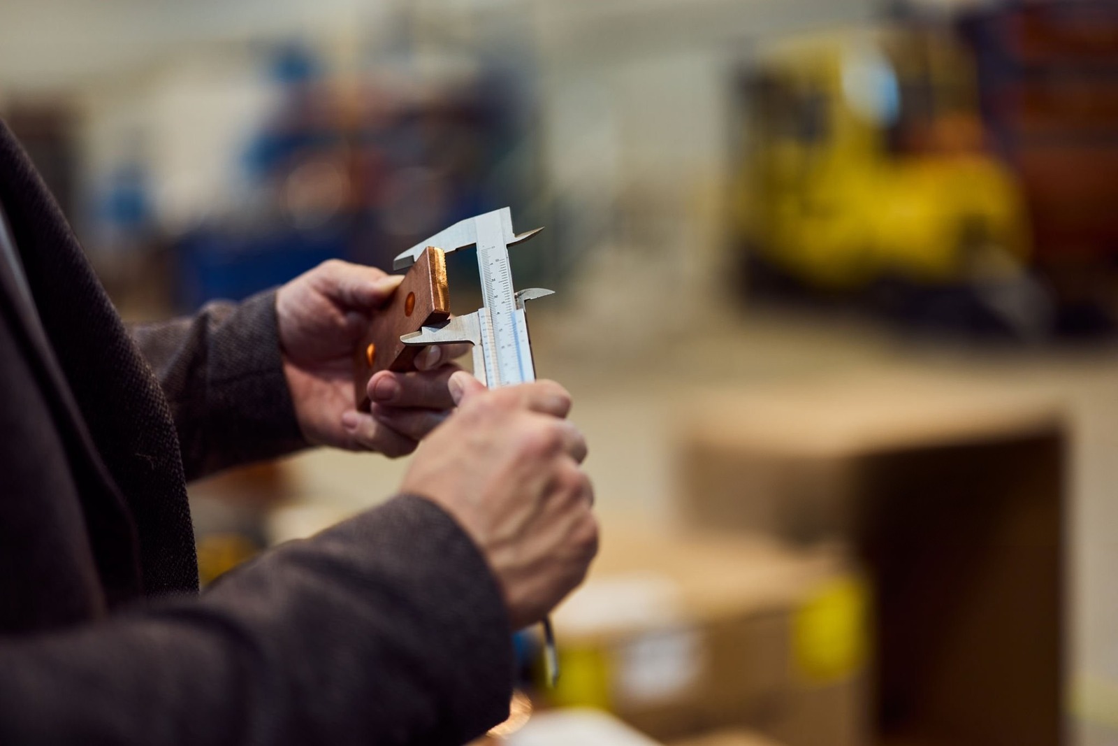 A machinist measuring a precision-machined part with calipers on the shop floor at Carpatians MFG in Troy, Michigan.