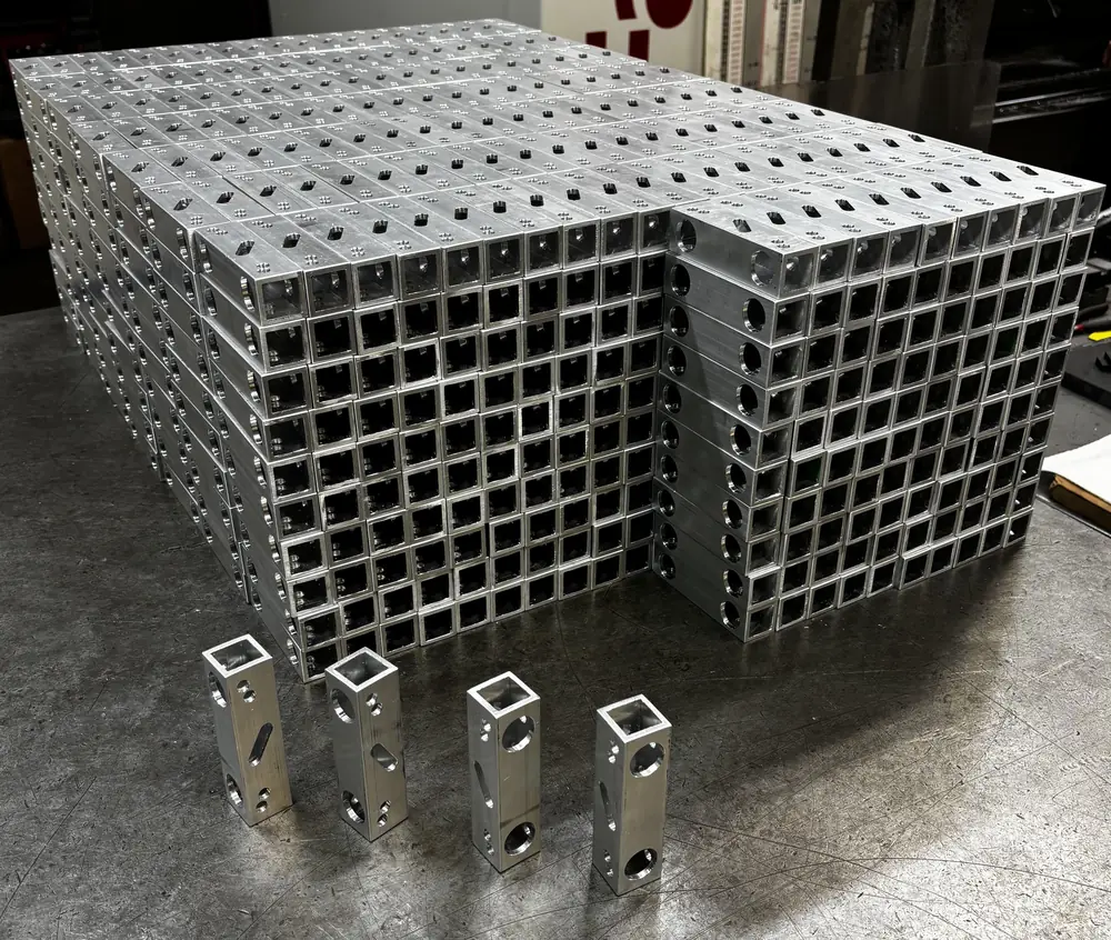 High-volume production run of CNC-machined aluminum components stacked and ready to ship from Carpatians Manufacturing in Troy, Michigan.